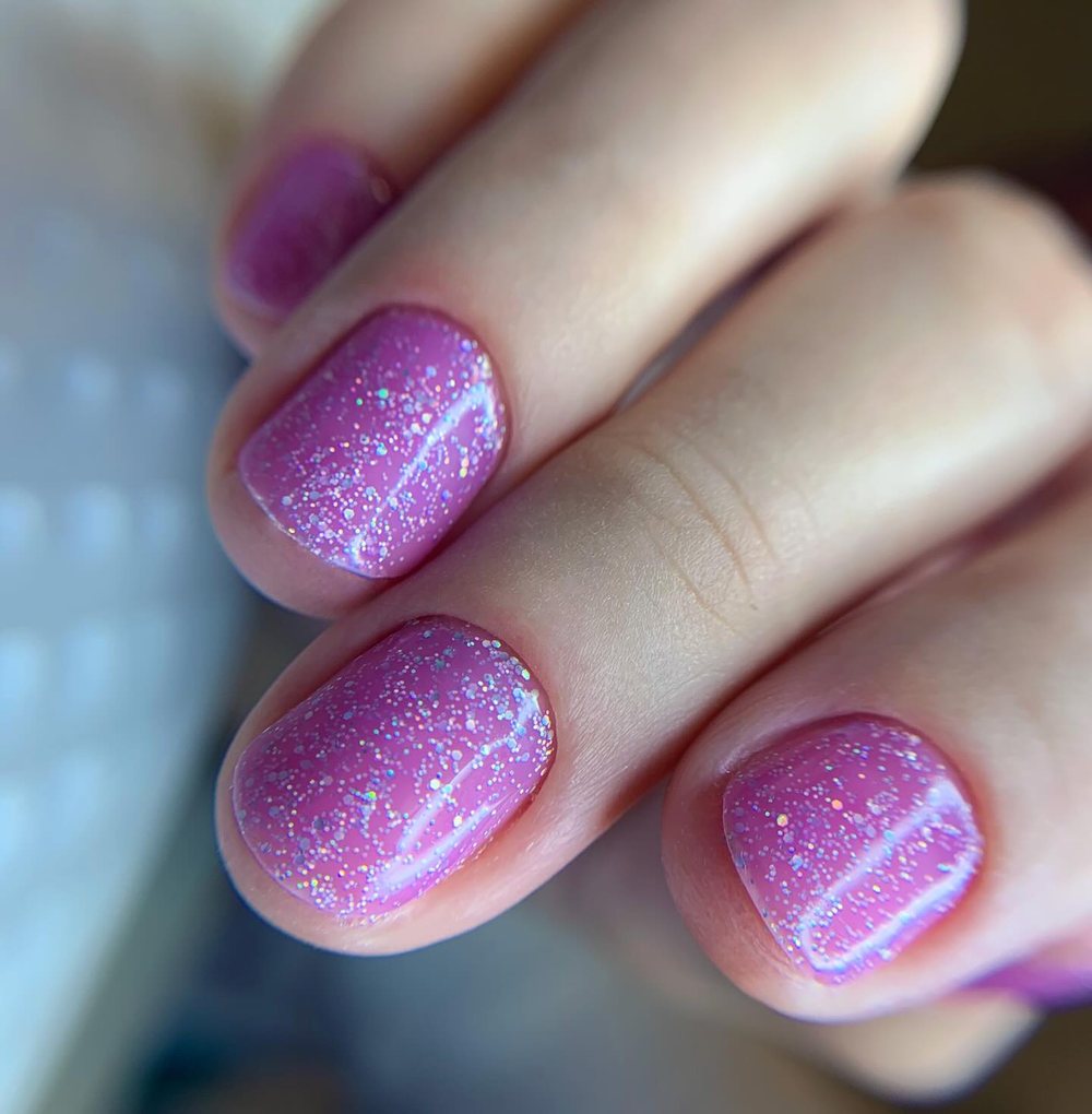 Unhas curtas com esmaltação em gel lilás cintilante