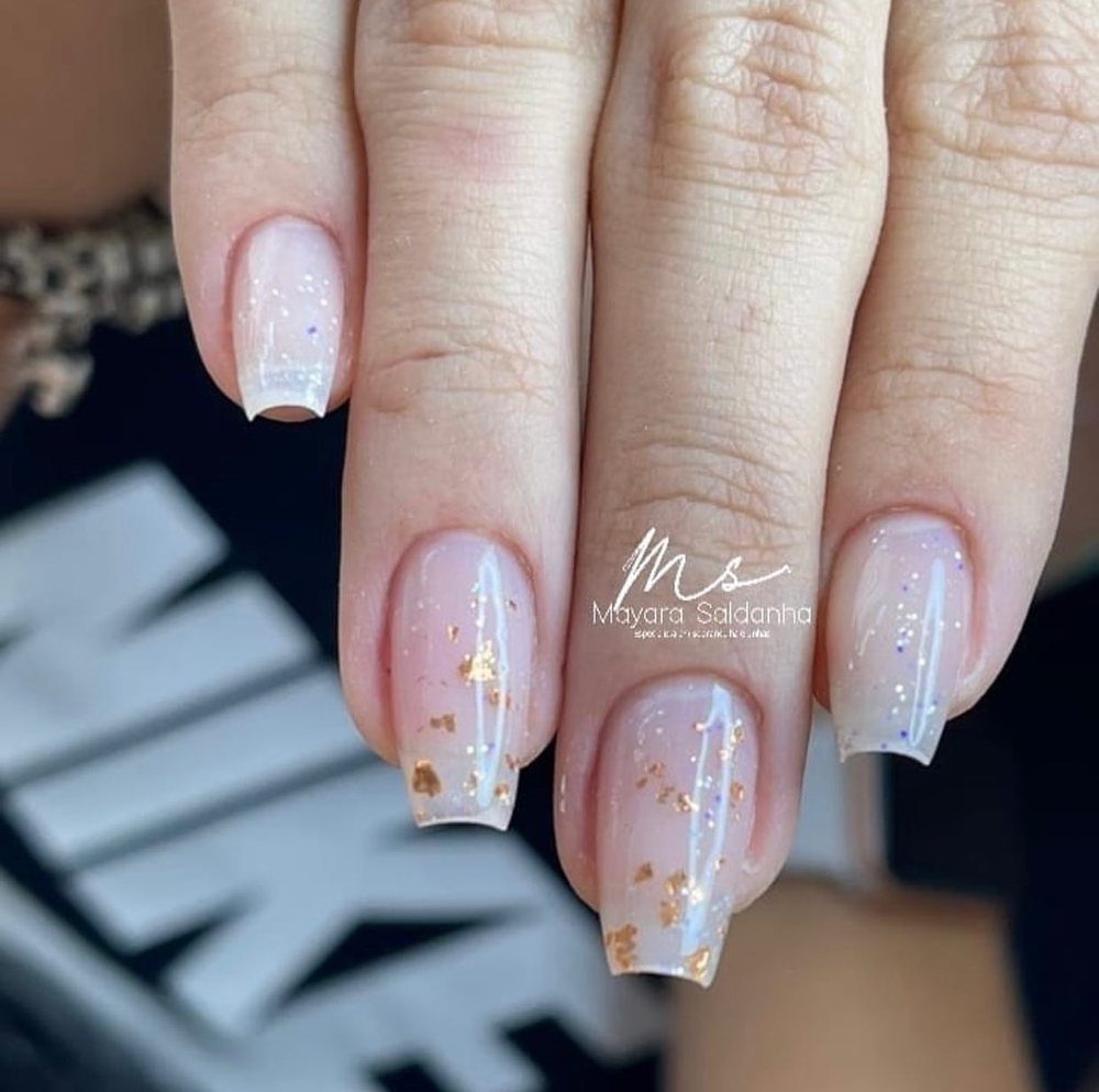 Unhas com esmaltação nude e detalhes em folha de ouro